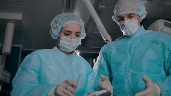 Two Surgeons in Robes Prepare Equipment for Surgery