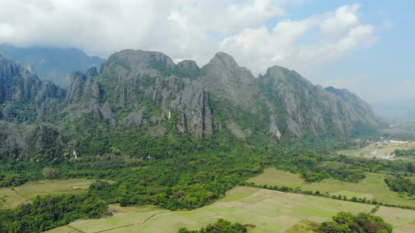 Aerial: flying over scenic cliffs rock pinnacles tropical jungle rice paddies