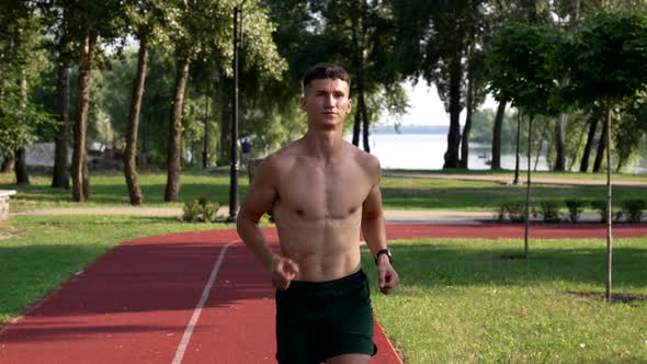 Sportive Guy with Muscular Body Runs on Running Track in Park Sporty