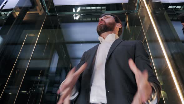 Stressed Angry Out Business Man Going Up From Office in a Glass Elevator