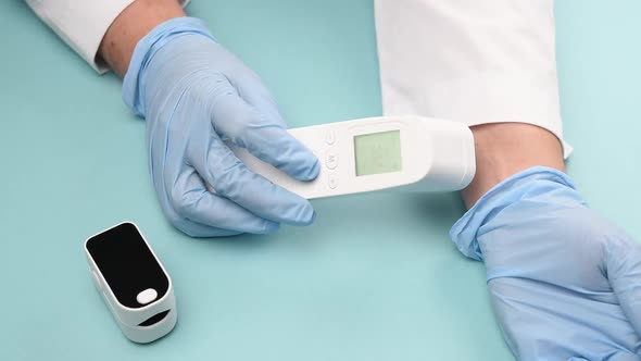 doctor in blue latex gloves measures body temperature on the wrist