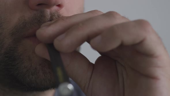 A man using a vape pen inhaling nicotine cannabis or flavoured CBD