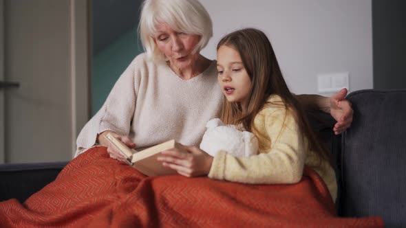 Handsome long-haired girl with her grandmother reading book