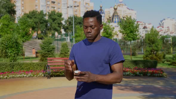 Portrait AfroAmerican Adult Man Standing in Park Wearing Wireless Earphones
