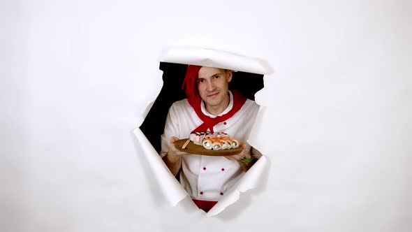 Young Man Dressed As Chef Holding Wooden Board with Sushi Rolls