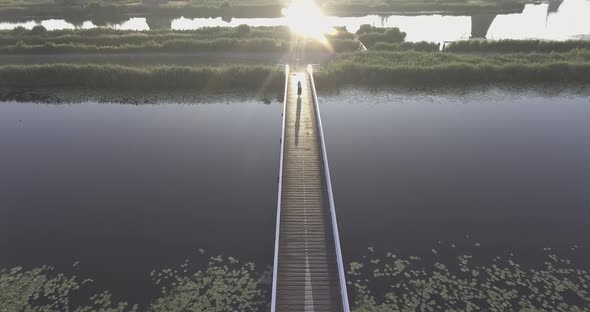 A drone shot panning down, while a girl walks on a bridge, with Dutch Windmills in the Netherlands d