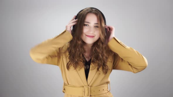 Portrait of a Young Lady Listening to Music By Headphones and Energy Dancing on White Background
