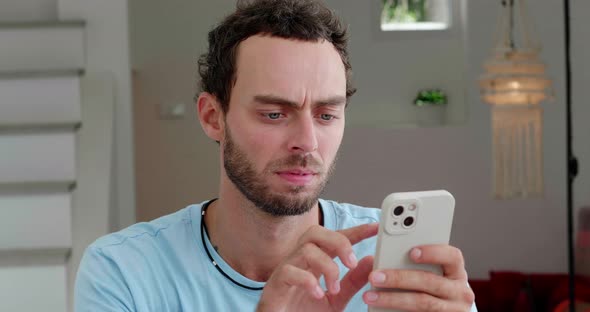 Handsome Caucasian Man in Casual Blue Tshirt Relaxing in the Home Interior Using Smartphone Types