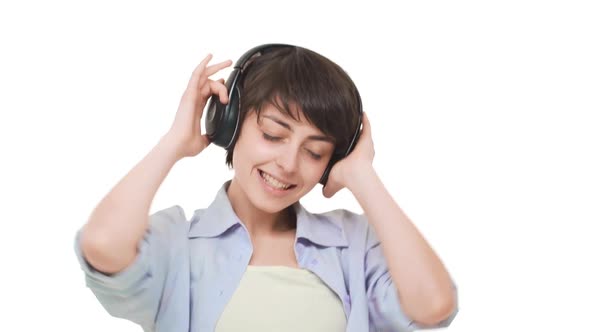 Young Caucasian Female with Short Haircut Listening Music Through Headphones with Pleasure Over
