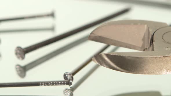 Mini Cutters with Yellow, Gray Handle on White Among Nails, Rotation, Reflection, Close Up