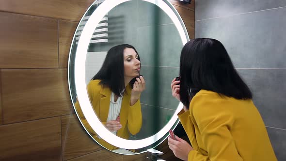 Business Woman in Stylish Suit Putting Pomade on Her Lips while Looking Into the Mirror