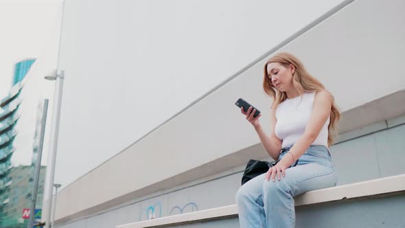 Young caucasian woman sitting outdoor using smartphone