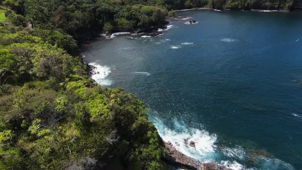 Bird's eye aerial over deep blue ocean water in cove, shot from FPV drone.