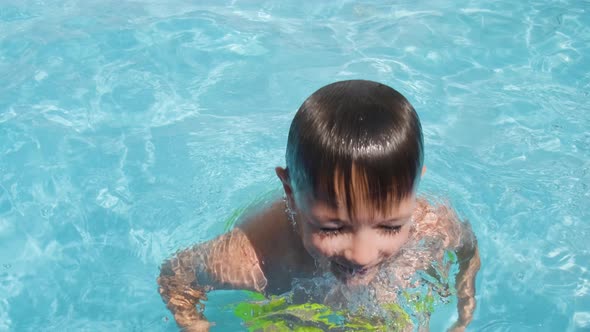 Caucasian boy emerges from pool water, happy kid looking into camera. summer Concept