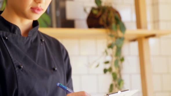 Beautiful waitress writing order in clipboard 4k