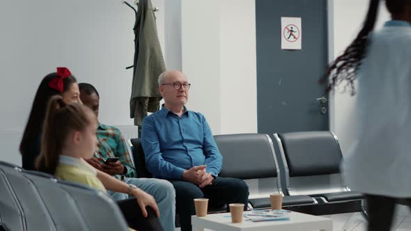 African American Man and Senior Patient Waiting Together at Hospital Reception