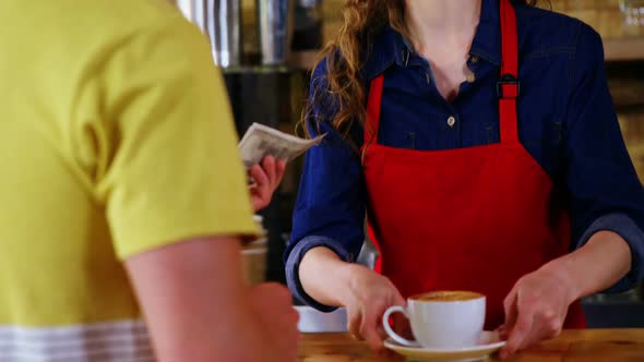 Female costumer paying bill to waitress at counter