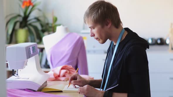 Fashion Designer with Notebook Drawing at Studio