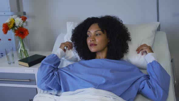 Mixed race woman lying in hospital bed fluffing her pillow