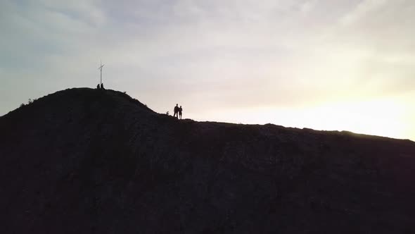 One man waves into the camera, as the drone rises the sun shines right in the camera.