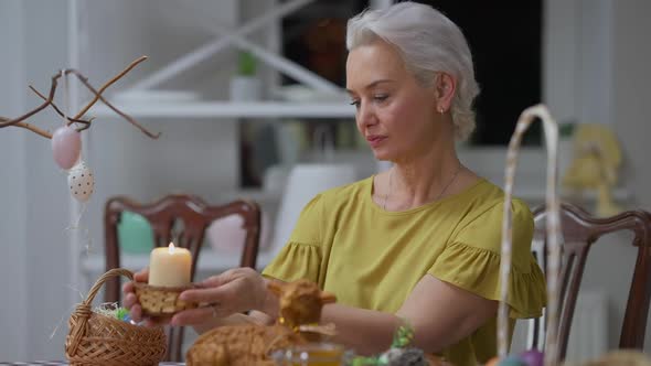 Medium Shot of Confident Serious Senior Woman Putting Burning Candle on Dinner Table Turning Looking