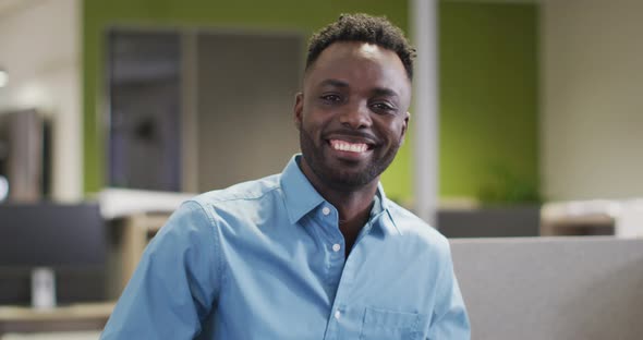 Video of happy african american businessman looking at camera in office