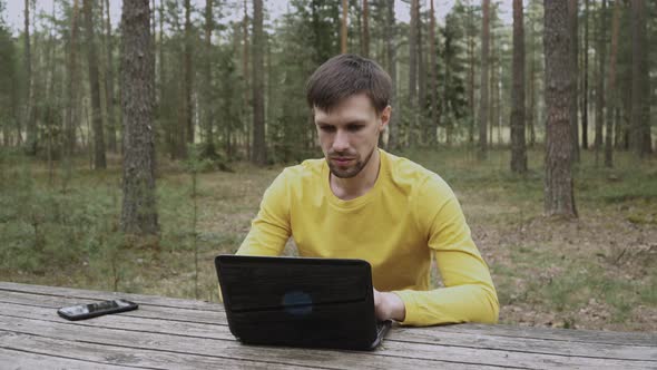 Man Working on Laptop in Forest