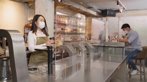 Woman customer receiving food from waitress with face mask on counter in restaurant during covid19.