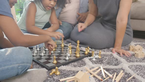 Happiness family with father and mother playing chess with children on floor together with fun.