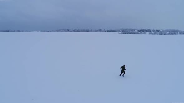 Man walking and running on a snowy field in Estonia.