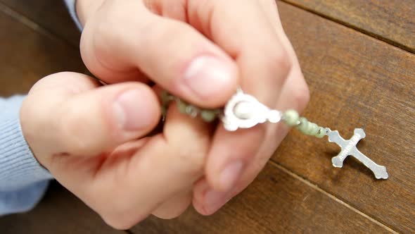 Praying hands holding rosary