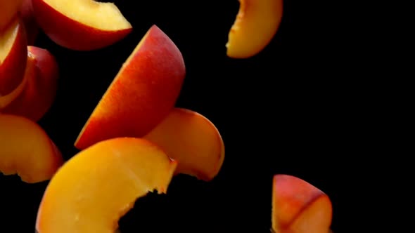 Closeup of the Slices of Peach are Falling Diagonally on the Black Background