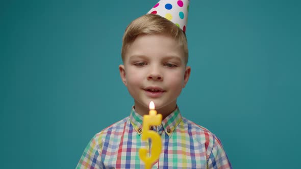 Kid in Birthday Hat Blowing Out Number 5 Candle in Slow Motion