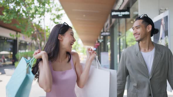 Asian young man and woman shopping goods outdoors in department store.