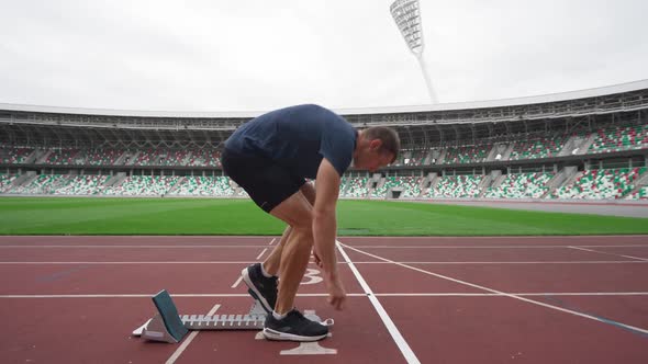 Stadium Man Sprinter is Preparing for the Start of a Training Run in Shortdistance Professional