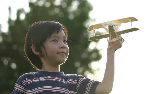 Cute Asian Child Playing Wooden Airplane In The Park Outdoors Slow Motion 