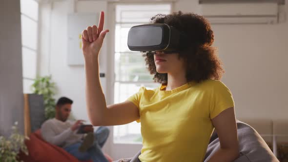 Mixed race woman wearing VR headset in creative office