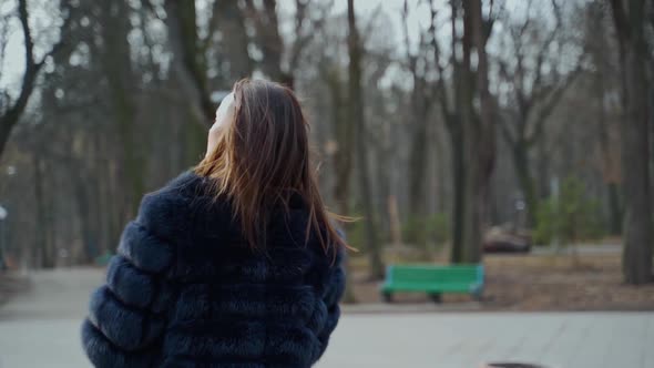 Young woman in fur coat in the park. 