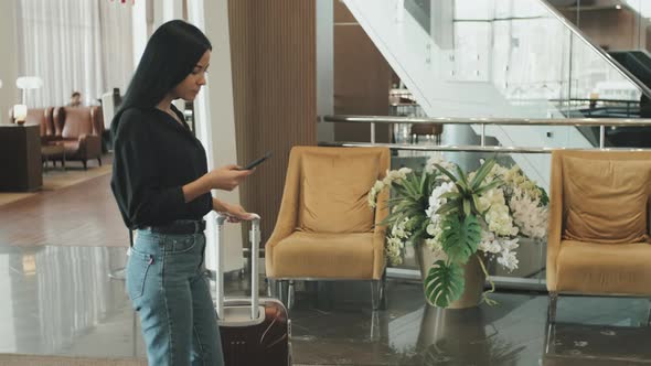 Woman with Smartphone Walking through Hotel Lobby