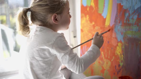 Little girl painting picture with paintbrush