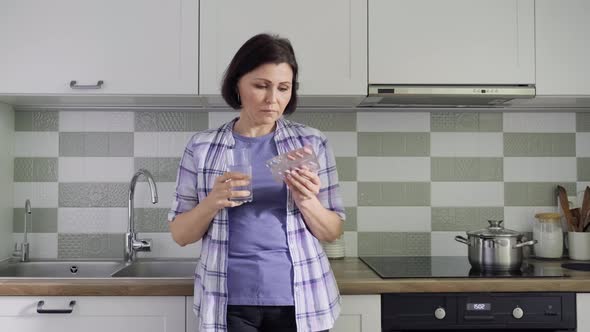 Middleaged Woman Drinking Vitamins Tablets Drinking a Glass of Water