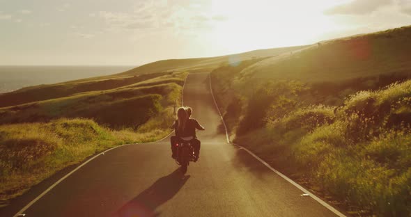 Couple riding vintage motorcycle at sunset