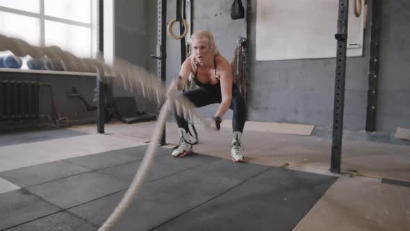 Woman Doing Battle Ropes Exercise in Gym alt