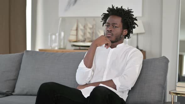 Young African Man Sitting at Home and Thinking 