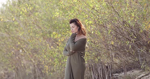 Beautiful female fashion model posing as she walks along the treeline