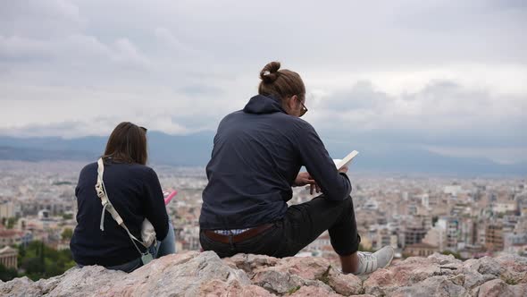 Female Tourists Spending Time on Reading Book on Old Acropolis Hill of Athens