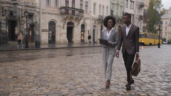 Two African Colleagues Walking and Talking on Street