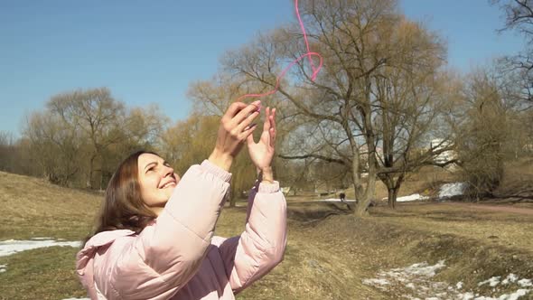 A Girl in a Pink Jacket Throws Up a Ball of Threads in an Autumn Spring Park Slow Motion