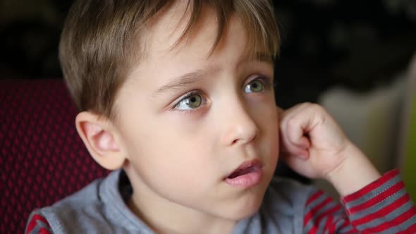 Portrait of a Pensive Boy Who Holds His Hand To His Ear