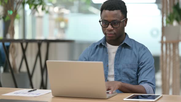 Young African Man Working on Laptop in Modern Office